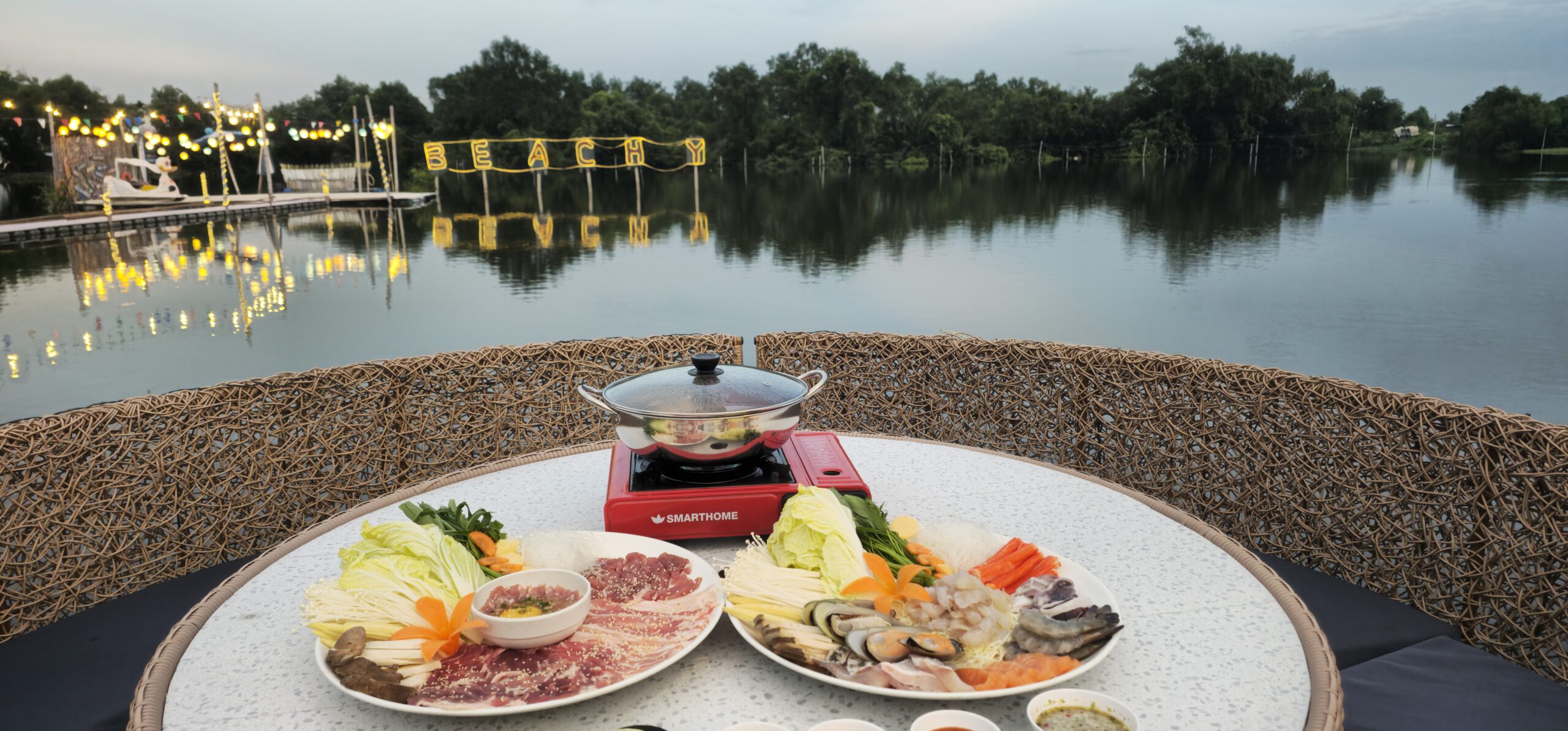 ชุดชาบูหม้อไฟริมทะเลสาบที่ร้าน Beachy พร้อมจานเนื้อสไลด์และอาหารทะเลสด บรรยากาศยามเย็นริมน้ำพร้อมไฟประดับ