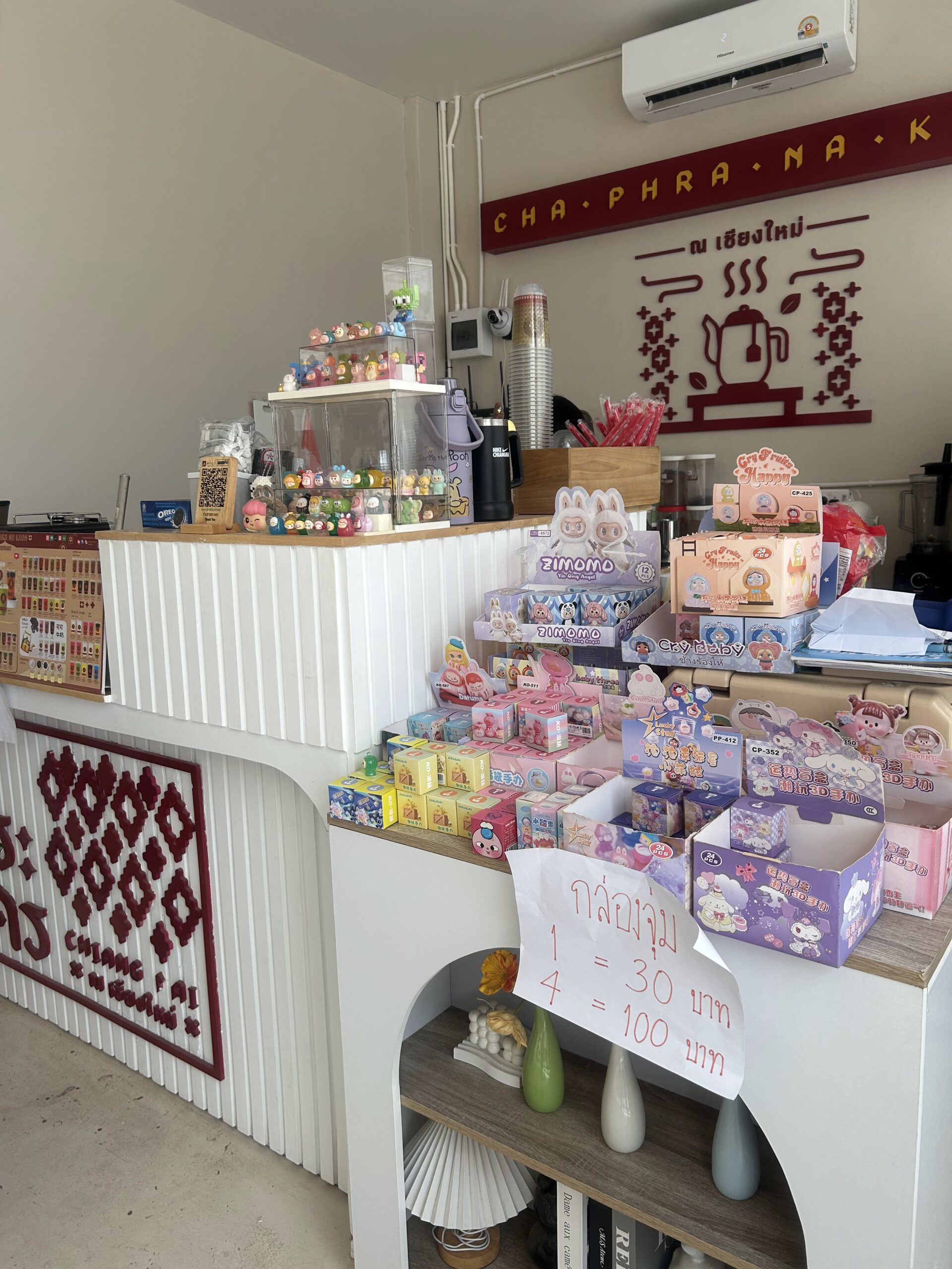 เคาน์เตอร์ร้านชาพระนค ณ เชียงใหม่ พร้อมกล่องสุ่มของเล่นและตุ๊กตาน่ารักหลากหลายแบบ ราคากล่องละ 30 บาท หรือ 4 กล่อง 100 บาท