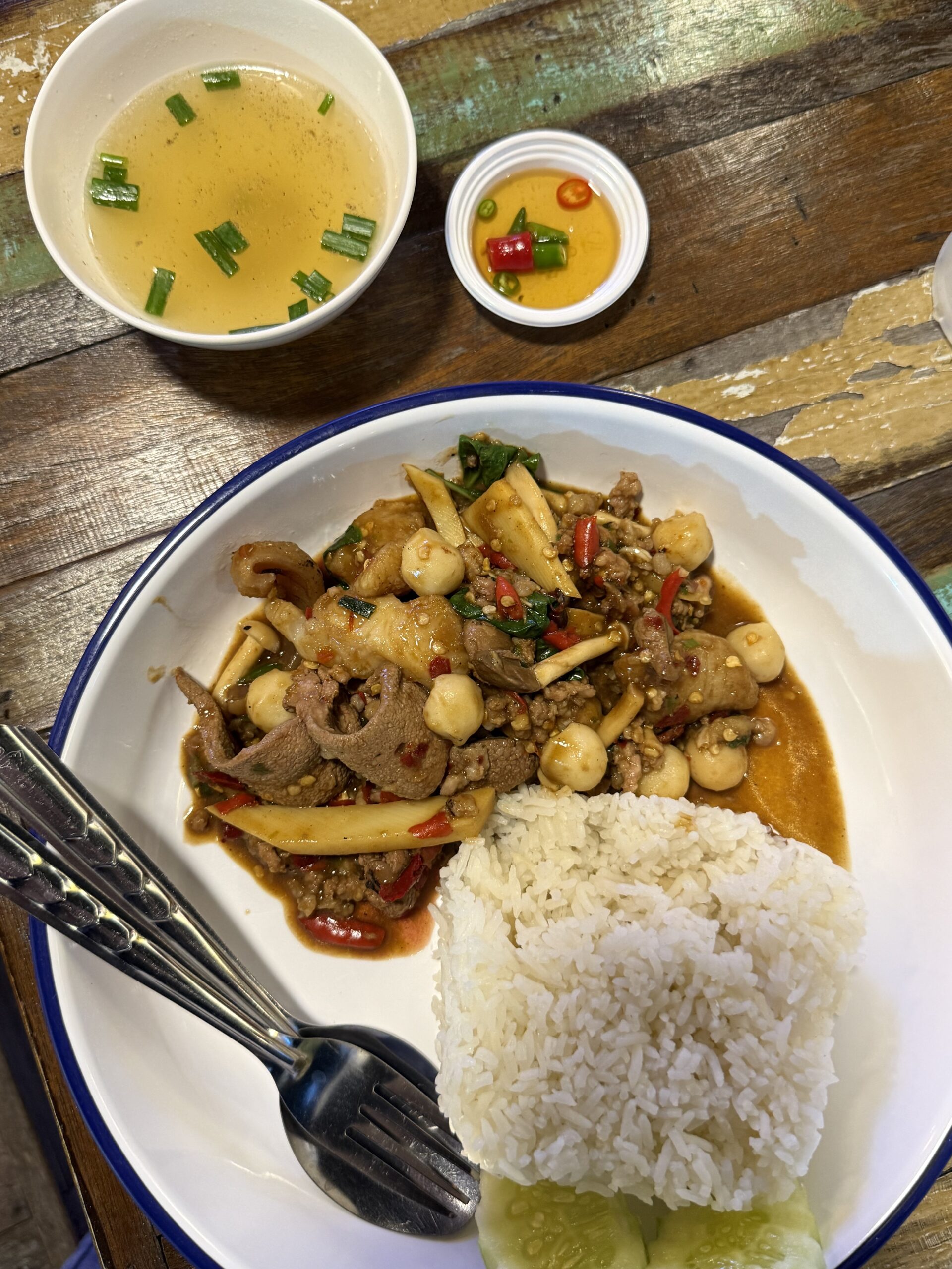 ข้าวราดผัดกะเพราเนื้อใส่เห็ดรวม พร้อมน้ำซุปและน้ำปลาพริก บนโต๊ะไม้