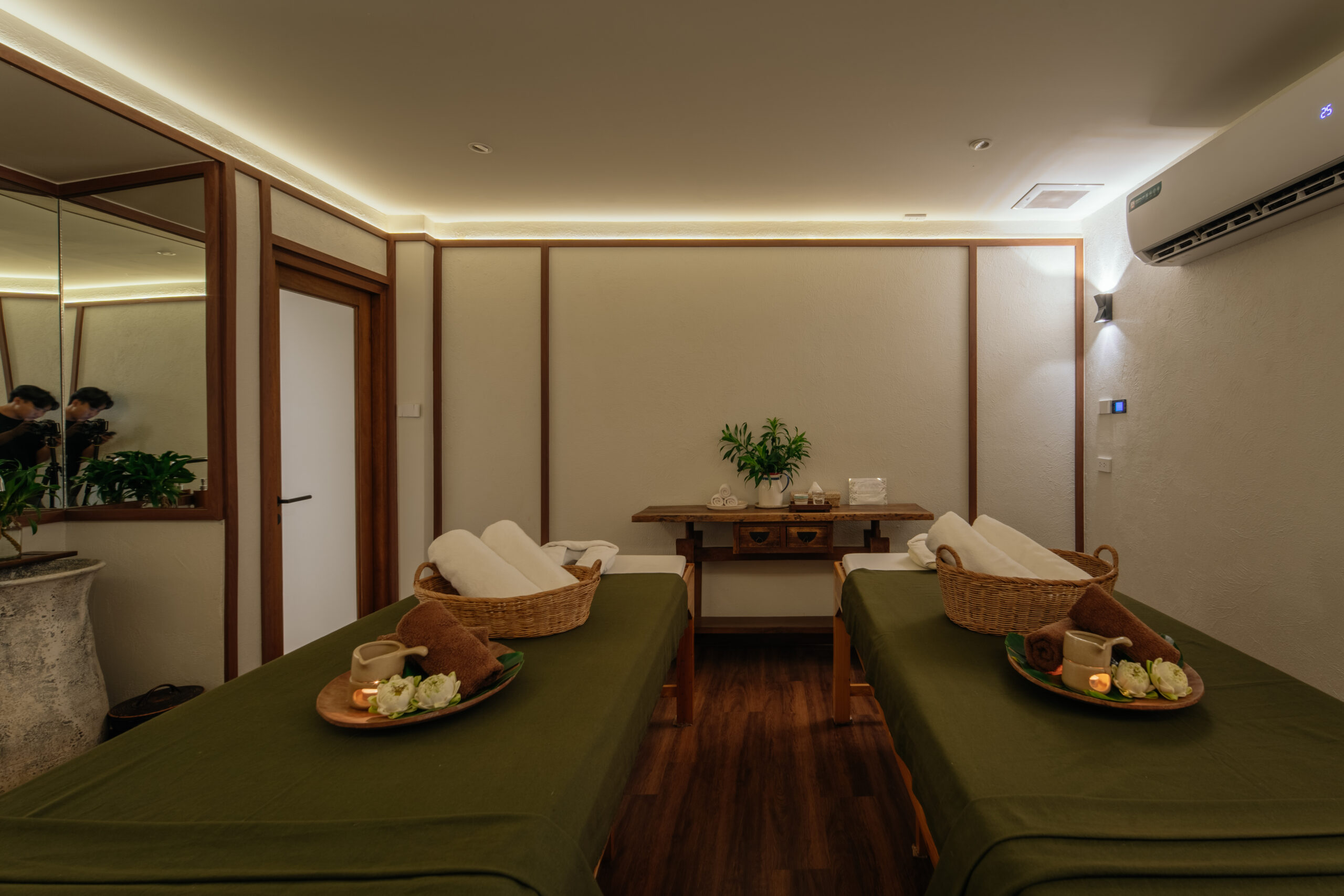 ห้องสปานวดคู่ตกแต่งสวยงามด้วยเตียงนวดสองเตียงคลุมผ้าสีเขียว พร้อมถาดดอกไม้และเทียนหอม บรรยากาศผ่อนคลาย