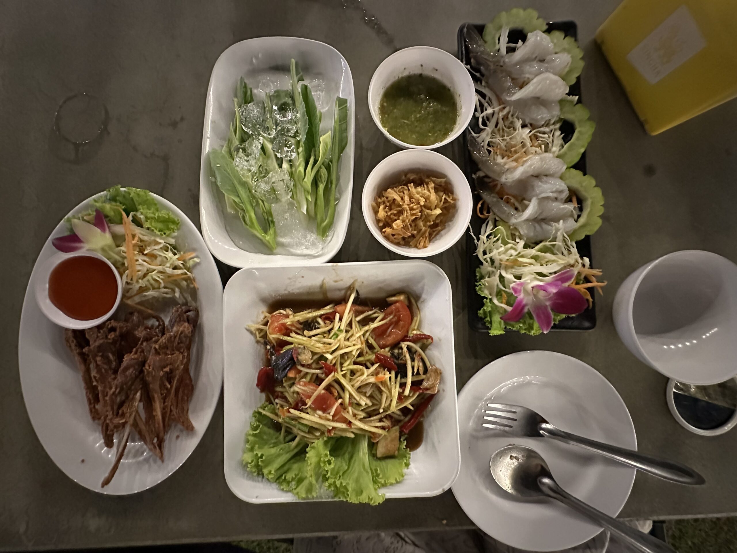 โต๊ะอาหารไทยจัดเต็มมีส้มตำ กุ้งแช่น้ำปลา ผักสดแช่น้ำแข็ง เนื้อทอดกรอบพร้อมน้ำจิ้ม และเครื่องเคียง