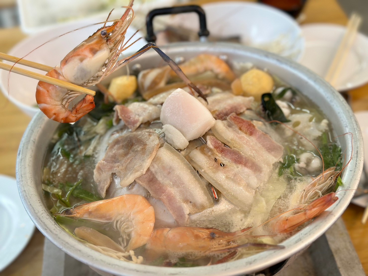 หม้อไฟทะเลรวมมิตรกับกุ้งสด เนื้อหมูสามชั้น ผักและเต้าหู้ทอด ใช้ตะเกียบคีบกุ้ง