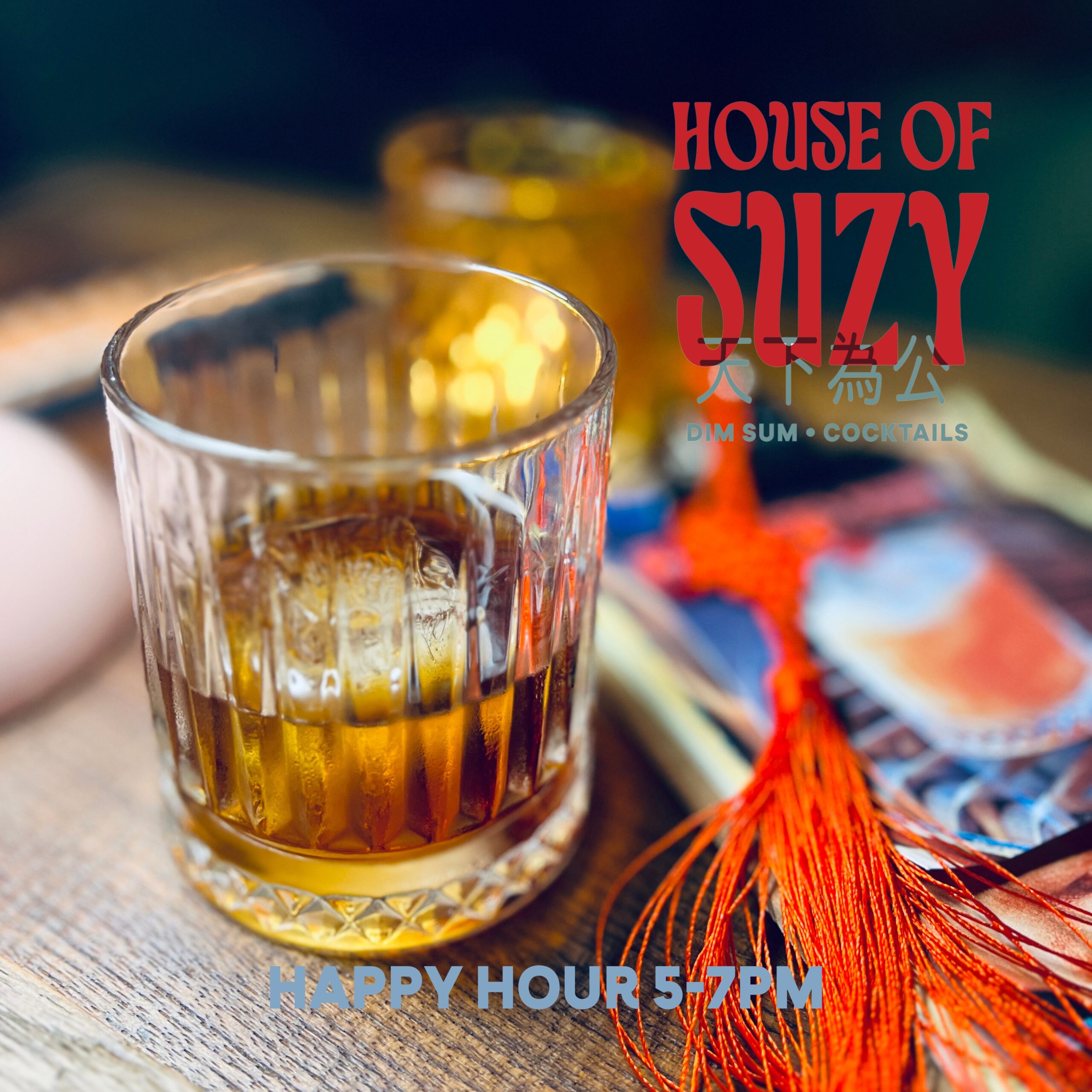 แก้วค็อกเทลวิสกี้สีอำพันในแก้วคริสตัลบนโต๊ะไม้ที่ร้าน House of Suzy ร้านติ่มซำและค็อกเทล พร้อมพู่สีแดงตกแต่งแบบจีน