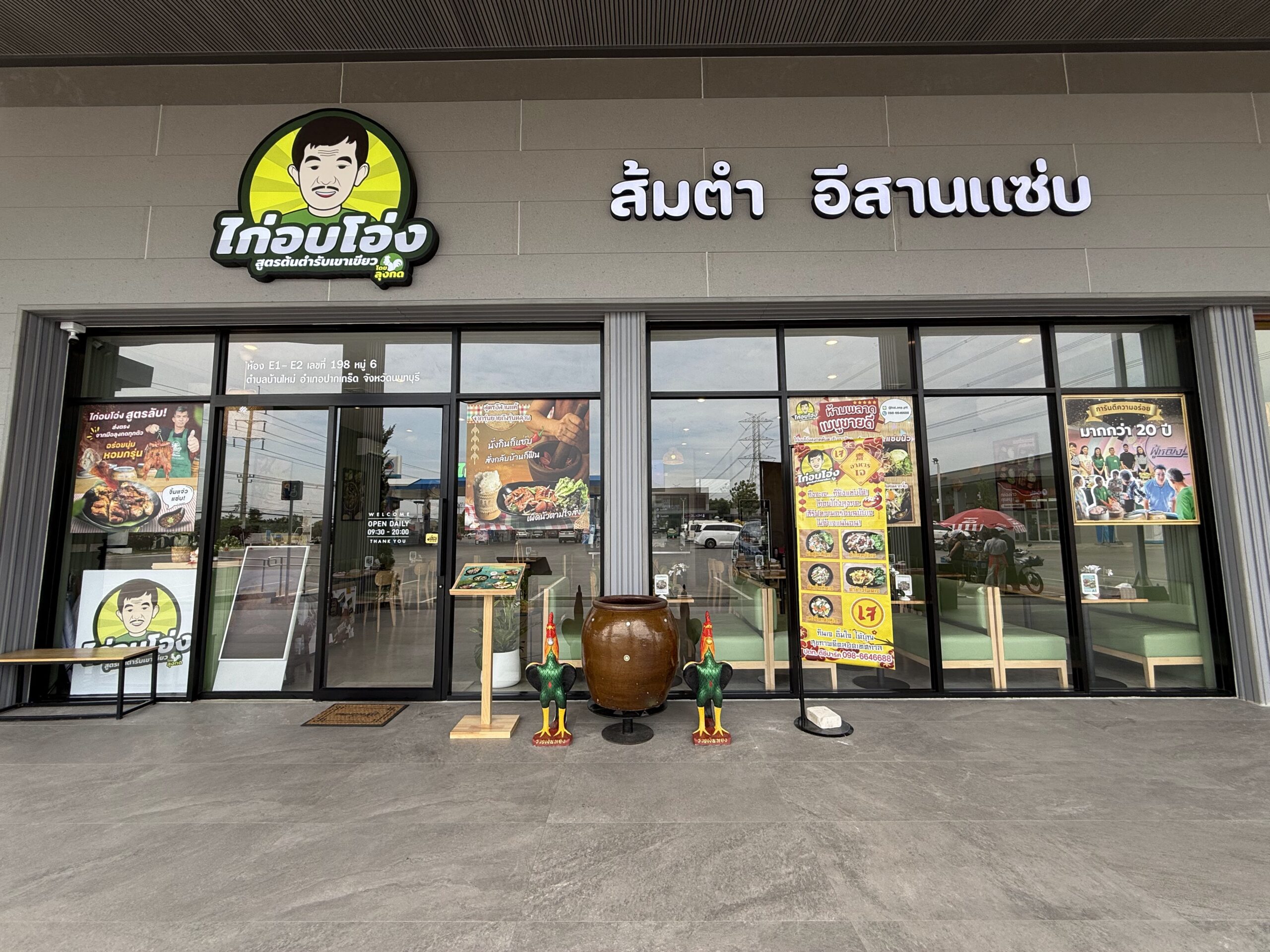 หน้าร้านไก่อบโอ่ง สูตรต้นตำรับเขาเขียว สาขาเพชรบุรี พร้อมป้ายส้มตำอีสานแซ่บ ตกแต่งด้วยโอ่งดินและไก่ปูนปั้น