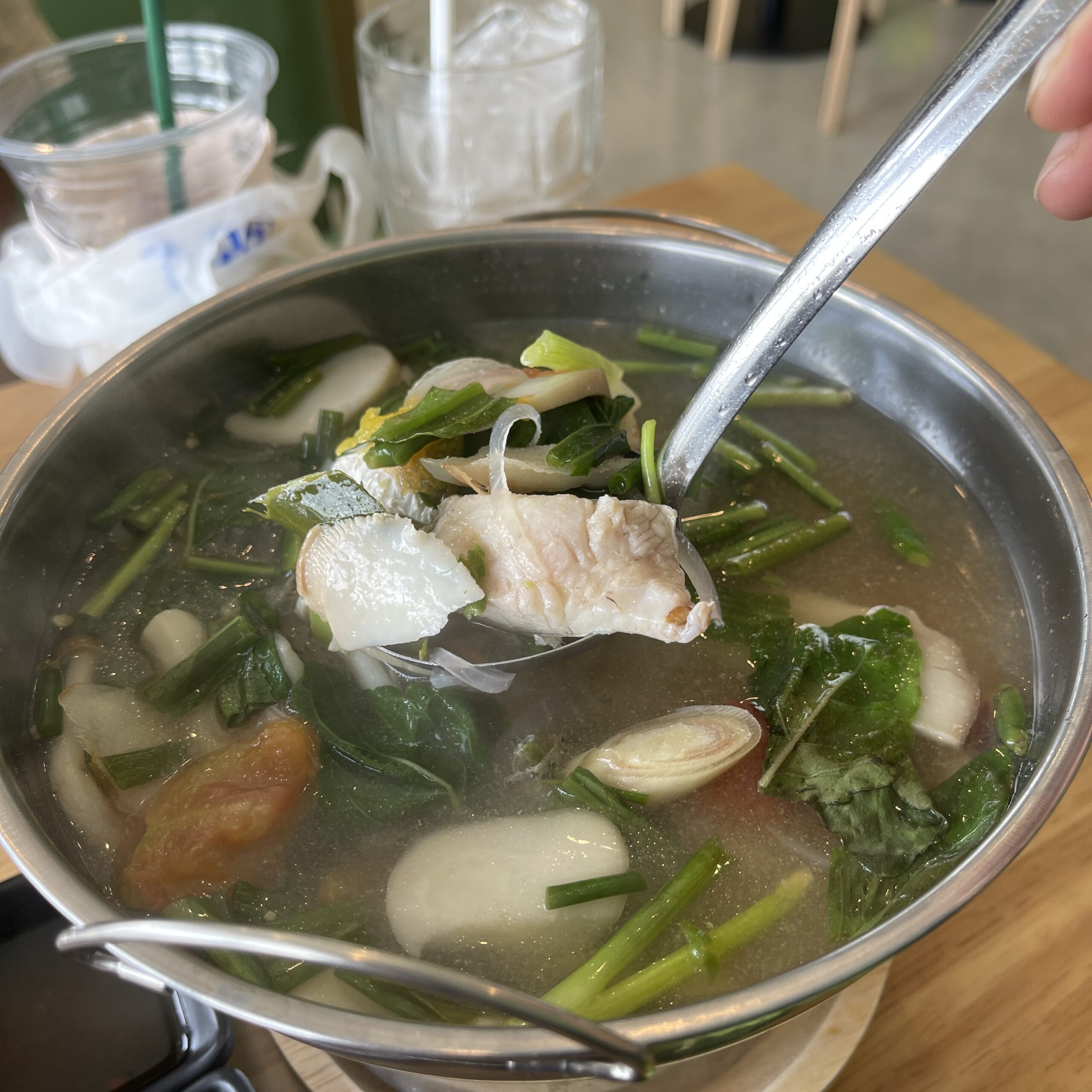 หม้อต้มปลาน้ำใสร้อนๆ กับผักบุ้ง เห็ด มะเขือเทศ และเนื้อปลาชิ้นโต เสิร์ฟในหม้อสแตนเลส