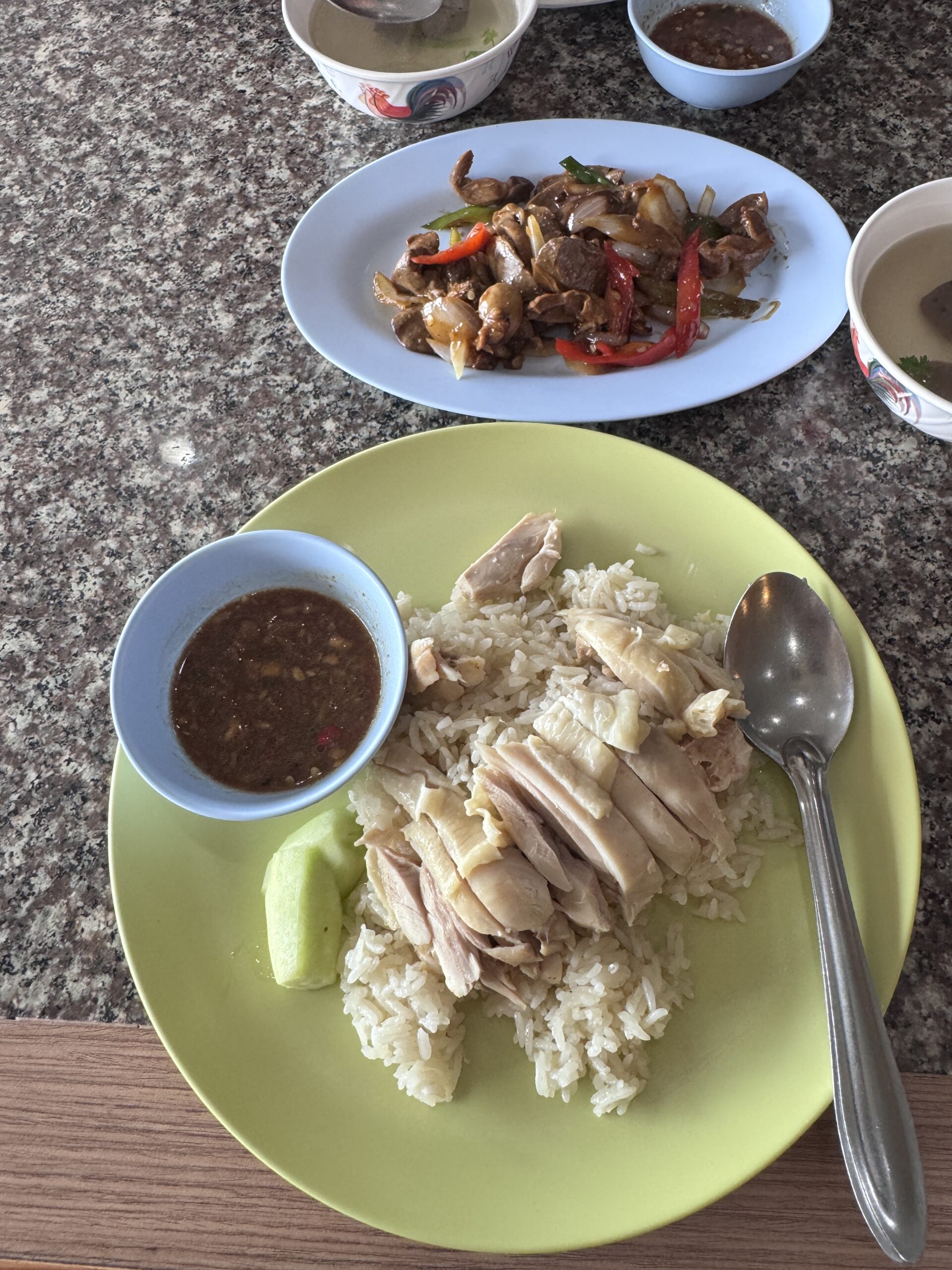 ข้าวมันไก่พร้อมน้ำจิ้มและผัดเครื่องในไก่บนโต๊ะหินอ่อน