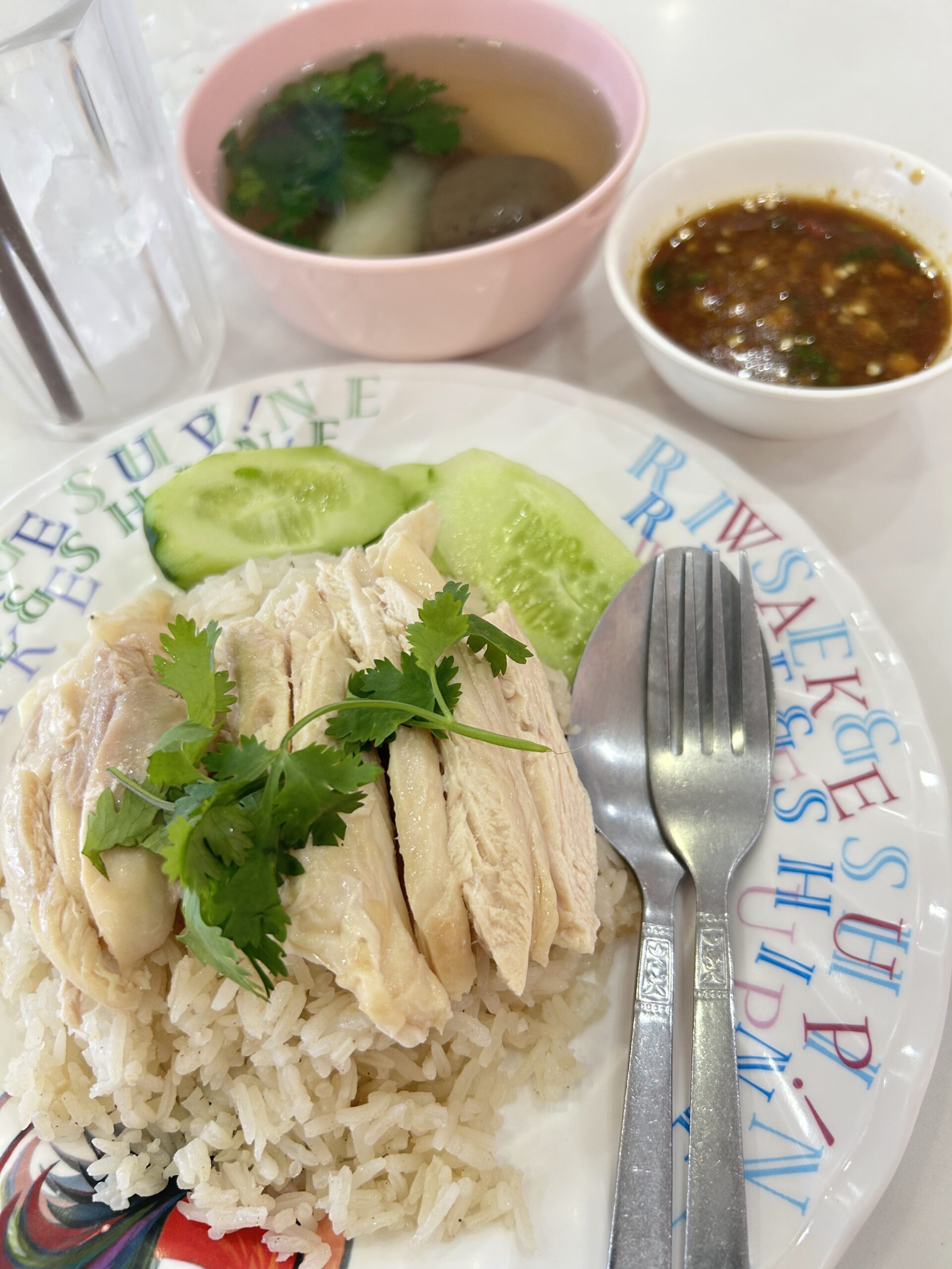 ข้าวมันไก่จานสวยพร้อมน้ำจิ้มและซุปเลือดหมูในชามสีชมพู เสิร์ฟบนจานตัวอักษรสีสัน