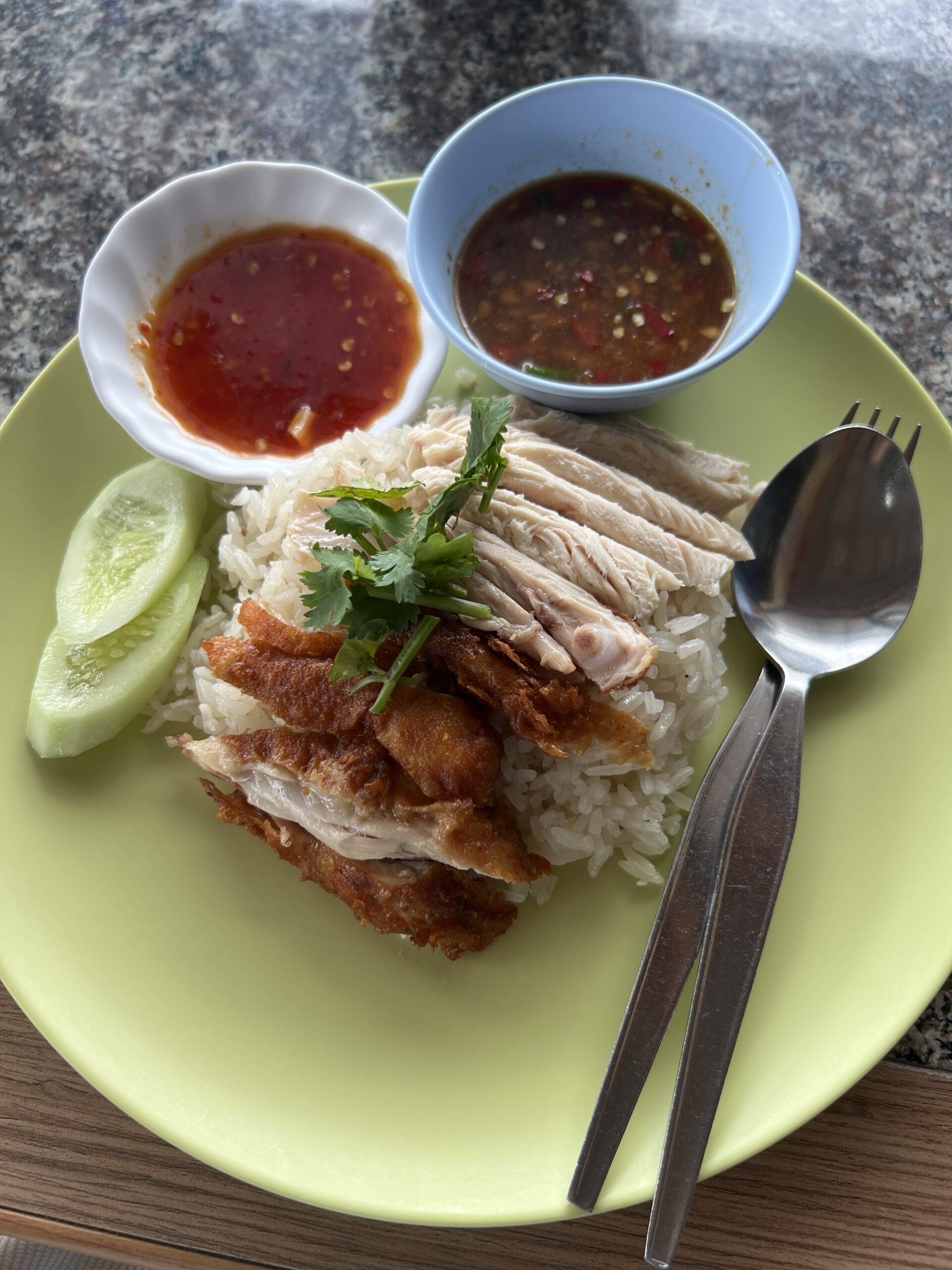 ข้าวมันไก่รวม ไก่ต้มและไก่ทอดบนข้าวมันพร้อมน้ำจิ้มสองถ้วยและแตงกวา บนจานสีเขียว