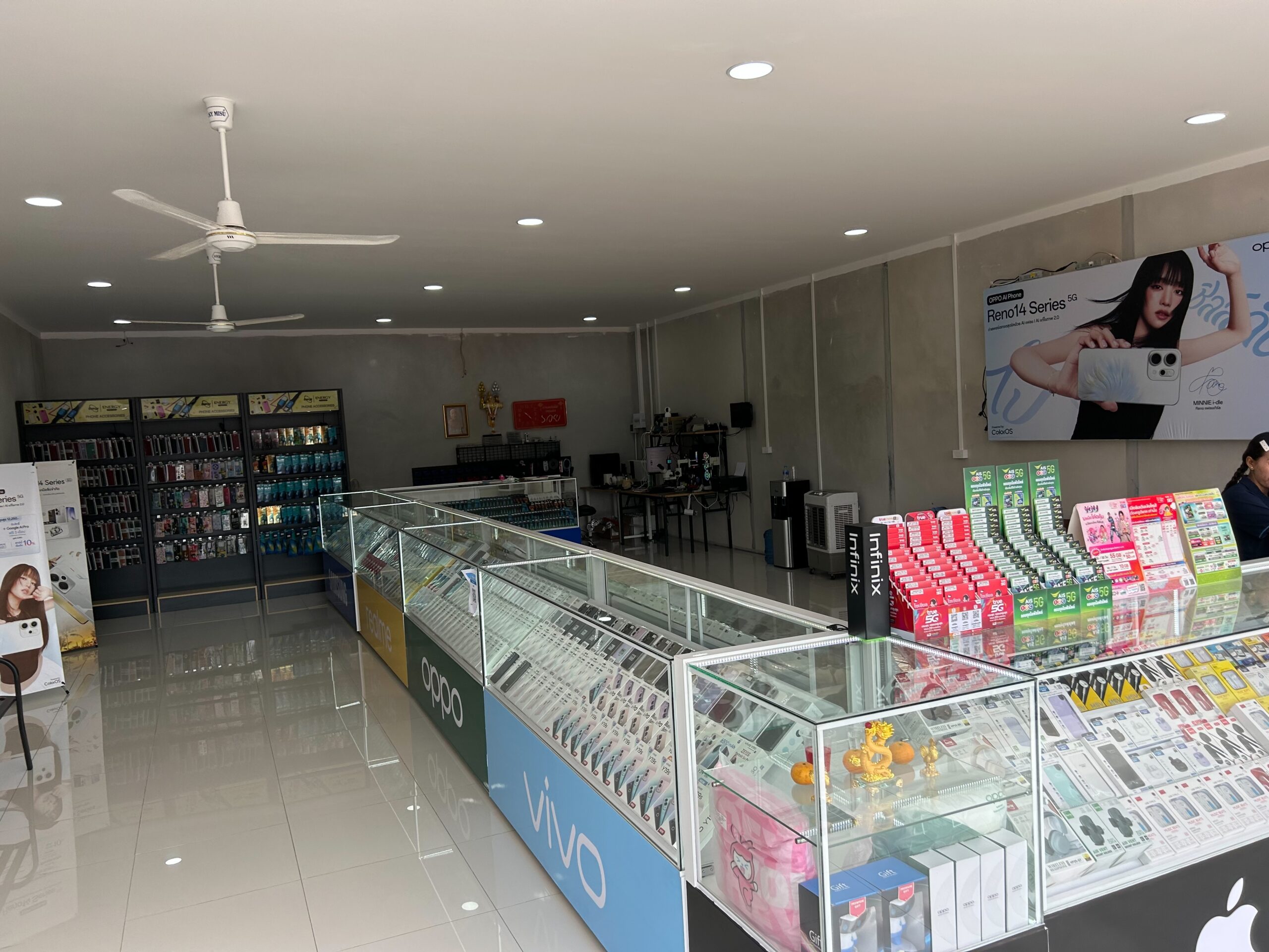 ภายในร้านขายโทรศัพท์มือถือที่มีตู้โชว์กระจกแสดงสินค้าแบรนด์ OPPO, Vivo, Infinix และอุปกรณ์เสริมต่างๆ