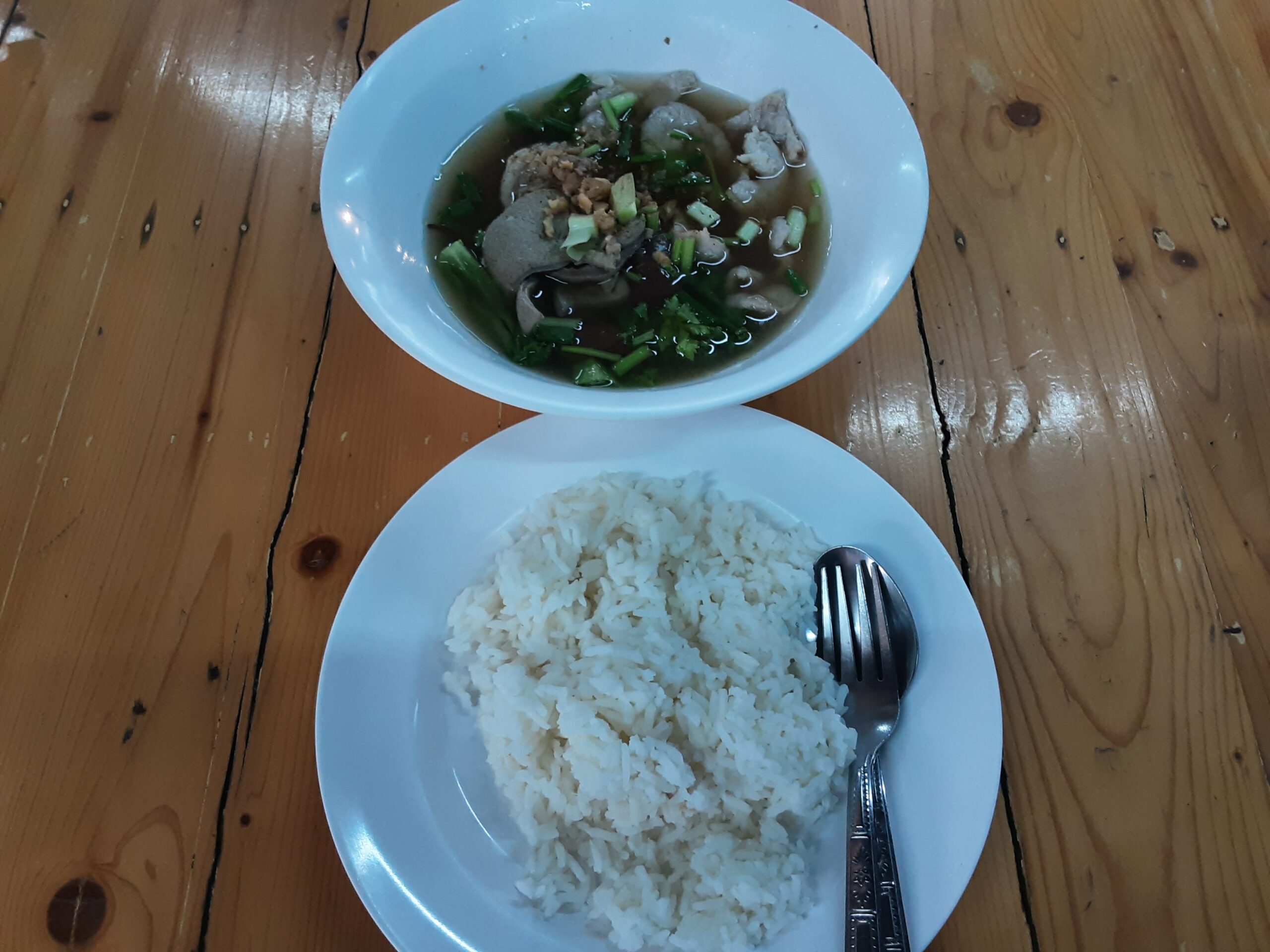 ข้าวสวยกับแกงจืดเครื่องในหมูใส่ผักบนโต๊ะไม้