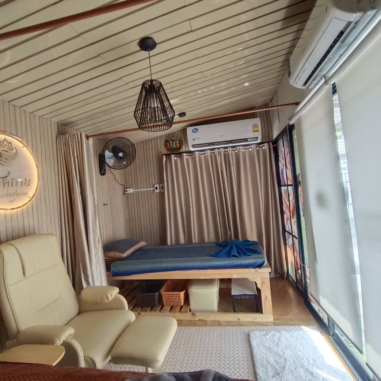 ห้องนวดแผนไทยตกแต่งสวยงามพร้อมเตียงนวด เก้าอี้นวด ม่านสีทอง แอร์ และพัดลม บรรยากาศอบอุ่นสบาย