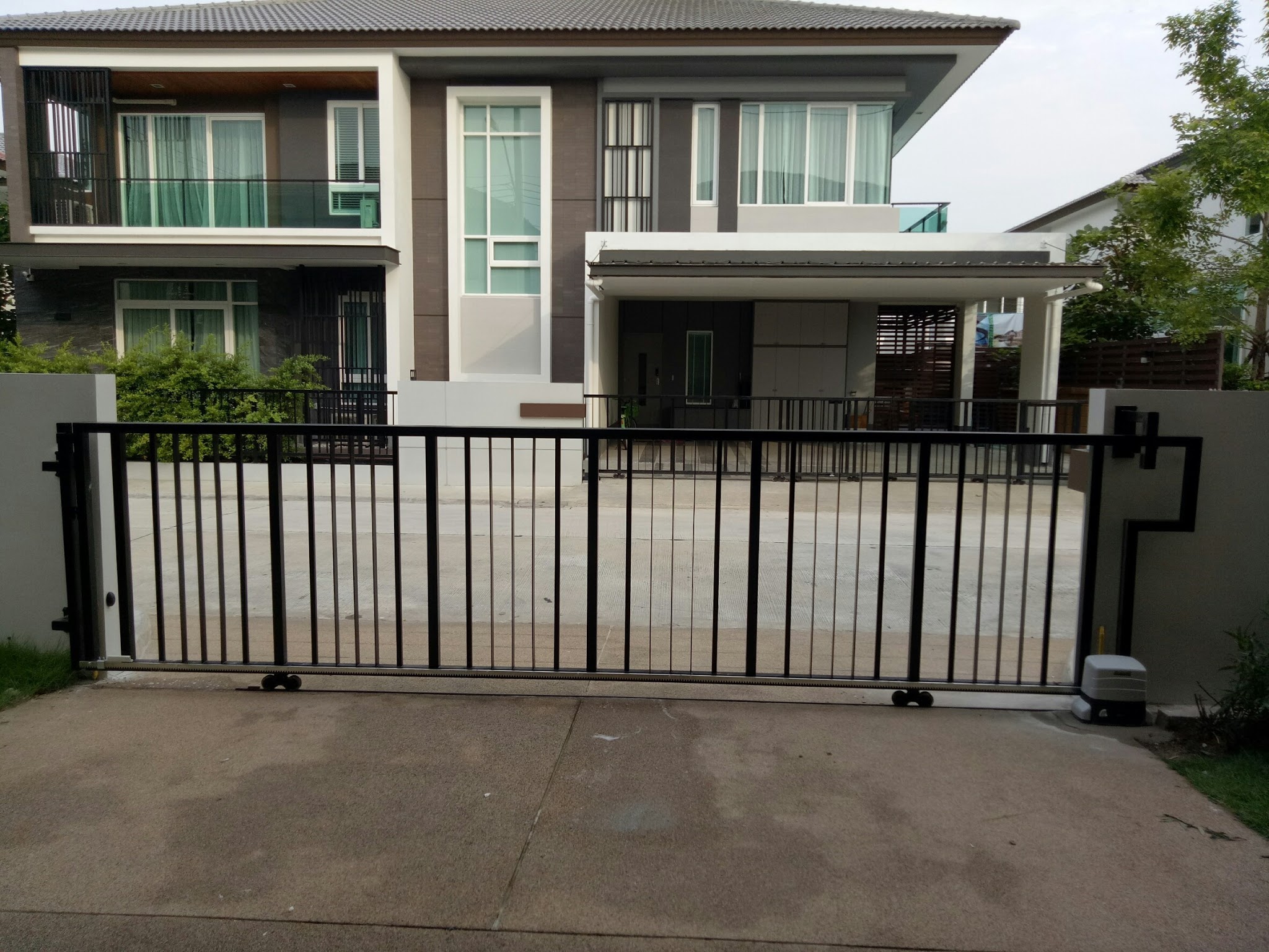 บ้านสองชั้นสไตล์โมเดิร์นพร้อมประตูรั้วเหล็กสีดำและทางเข้ารถ