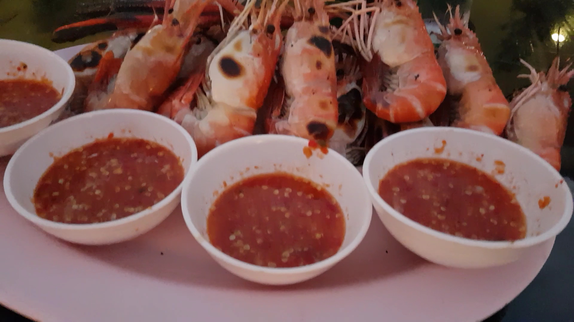 กุ้งแม่น้ำเผาจัดเสิร์ฟบนจานพร้อมน้ำจิ้มซีฟู้ดรสเด็ดในถ้วยสีขาว 4 ถ้วย