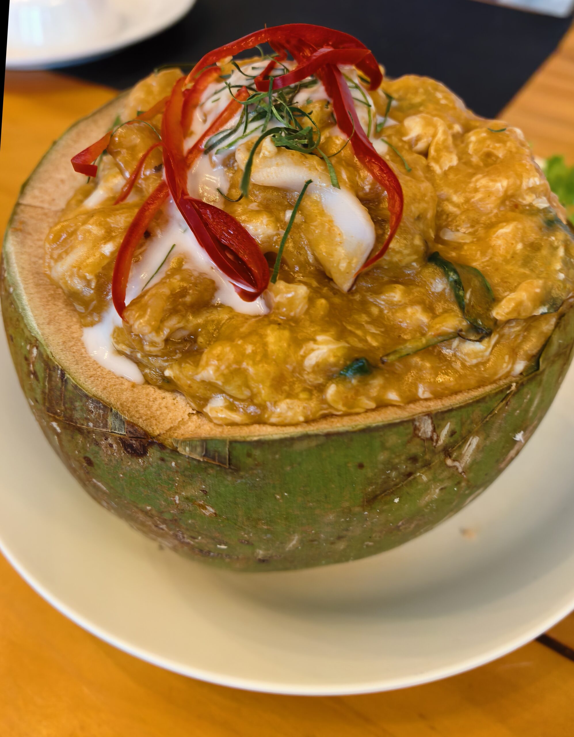 ห่อหมกทะเลเสิร์ฟในกะลามะพร้าวสดตกแต่งด้วยพริกแดงซอยและใบมะกรูดราดกะทิ