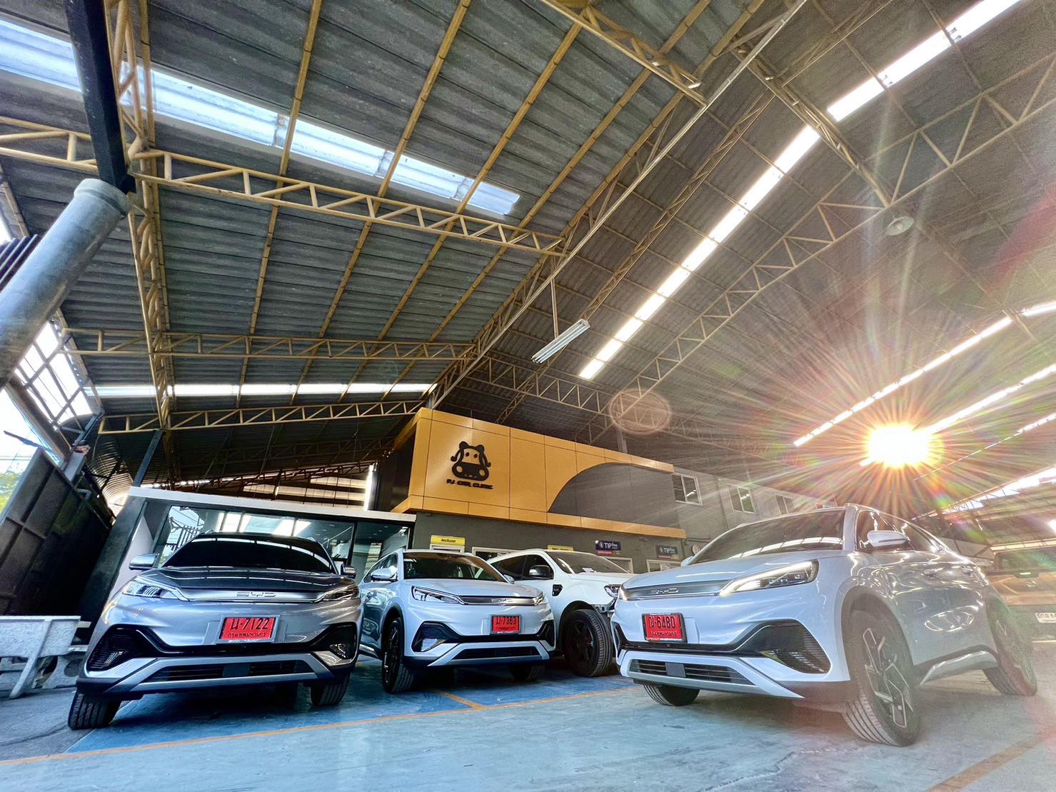 รถยนต์ BYD สีขาวหลายคันจอดเรียงกันในโชว์รูมโกดังขนาดใหญ่พร้อมป้ายทะเบียนแดง