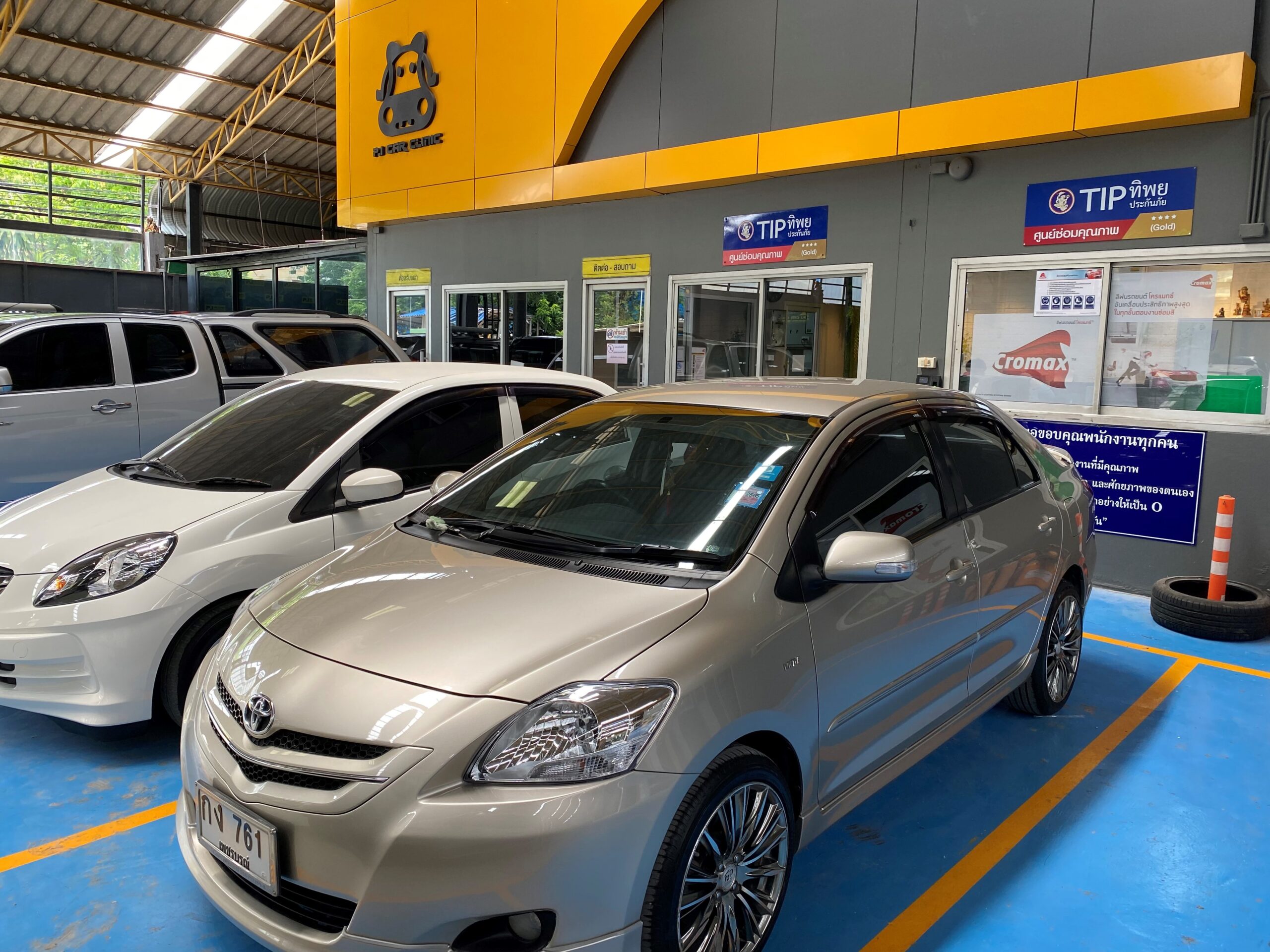 รถยนต์โตโยต้าสีเงินจอดอยู่ในศูนย์ซ่อมรถยนต์ PD Car Clinic ที่มีป้าย TIP ทิพย์ประกันภัยและ Cromax