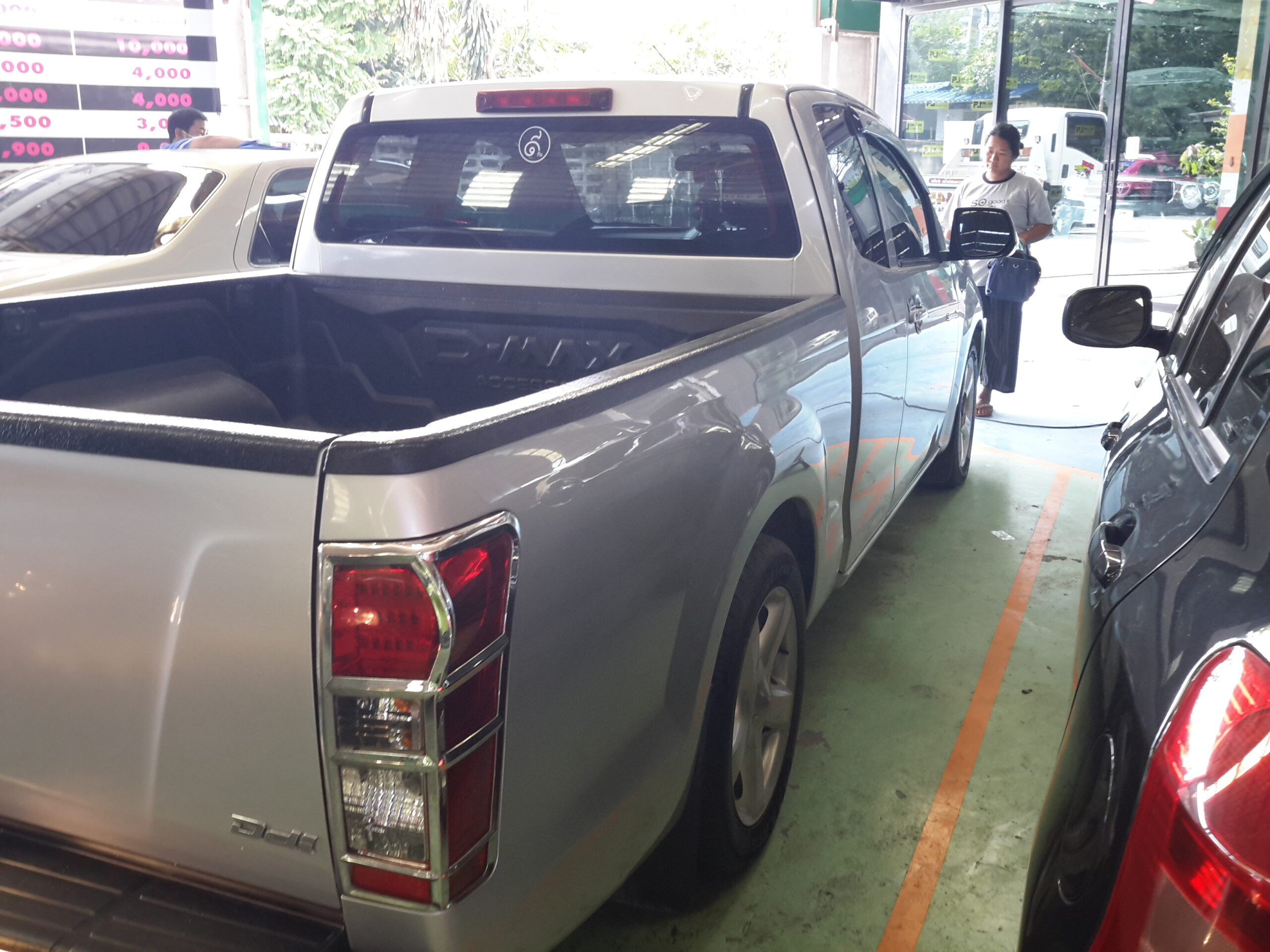 รถกระบะสีเงินจอดในลานจอดรถใกล้อาคารพาณิชย์