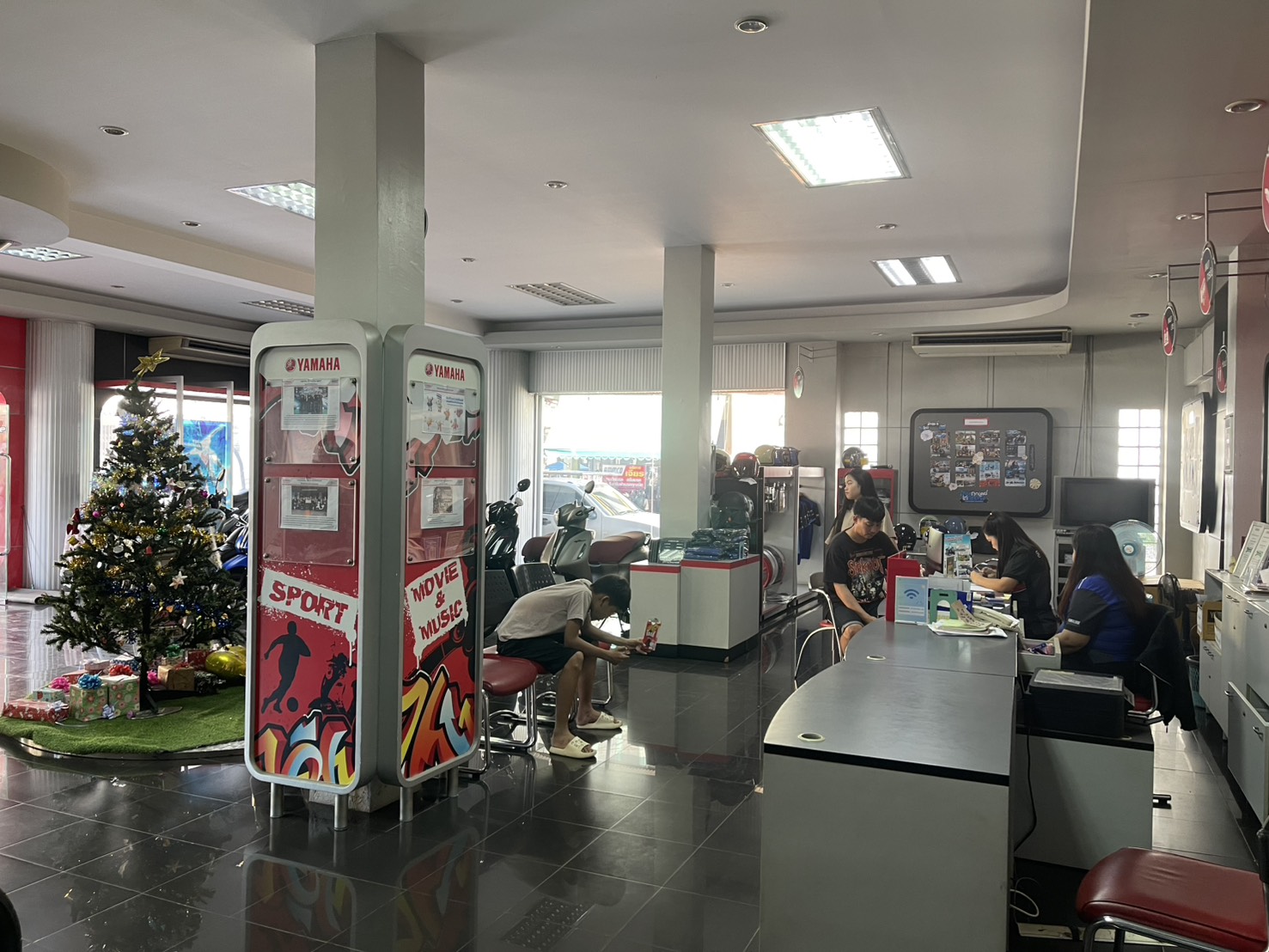 ภายในโชว์รูมตัวแทนจำหน่ายยามาฮ่า มีต้นคริสต์มาส ตู้โฆษณา และเคาน์เตอร์บริการลูกค้า