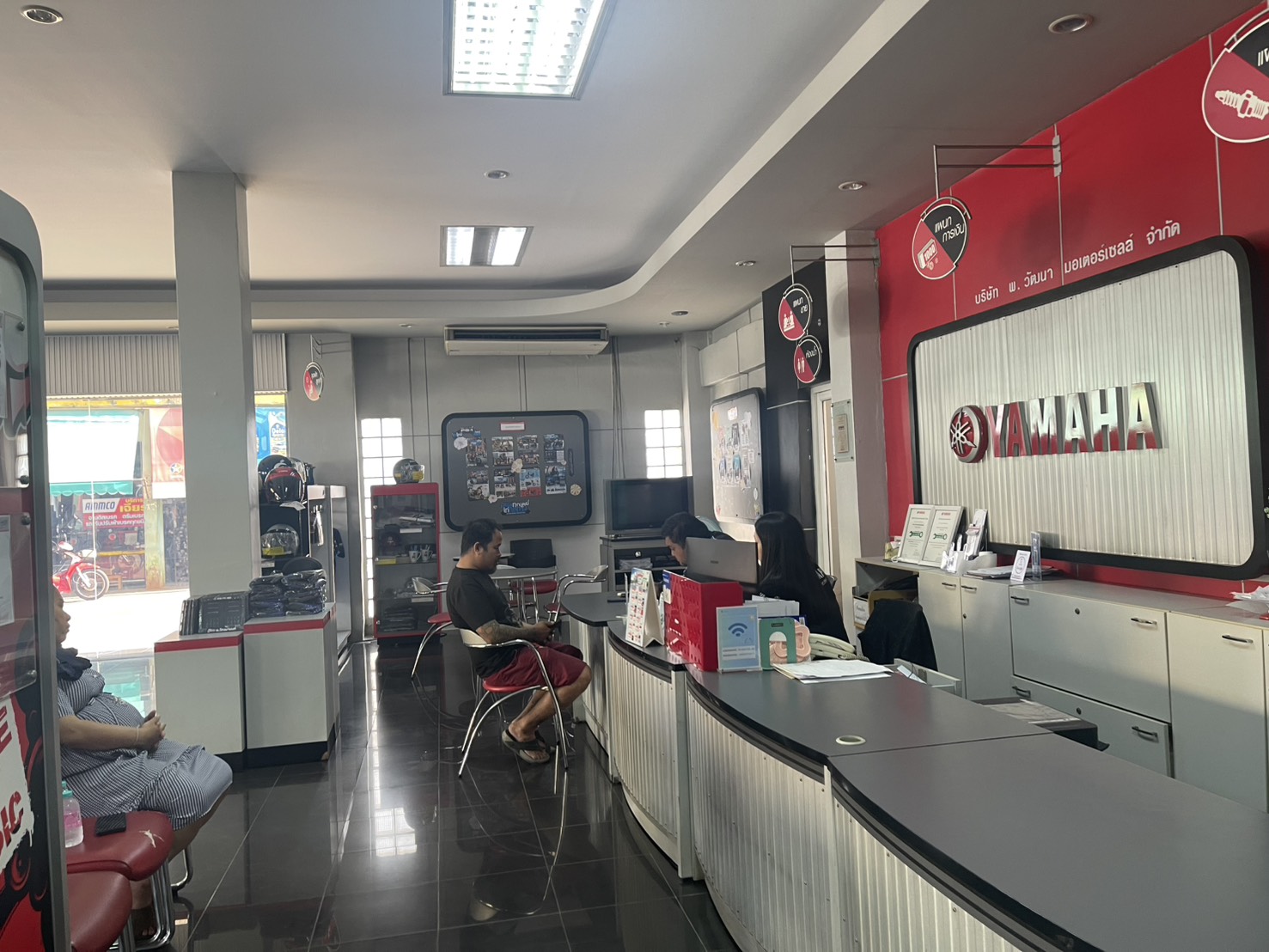 ภายในศูนย์บริการยามาฮ่า พ.วัฒนา มอเตอร์เซลล์ จำกัด มีเคาน์เตอร์บริการลูกค้าและพนักงานกำลังให้บริการ