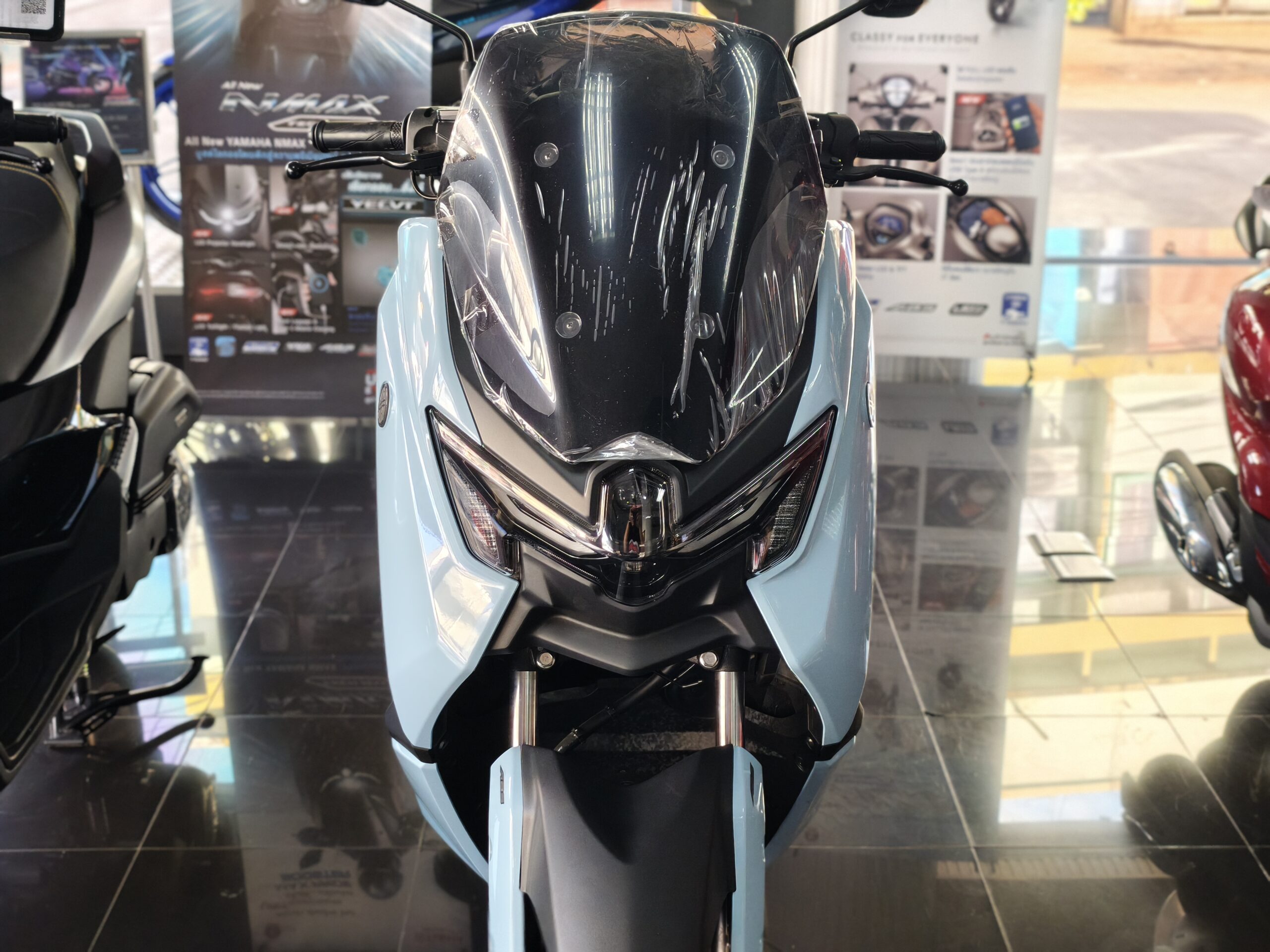 รถมอเตอร์ไซค์ยามาฮ่า NMAX สีฟ้าอ่อนจอดโชว์ในโชว์รูมมองจากด้านหน้า