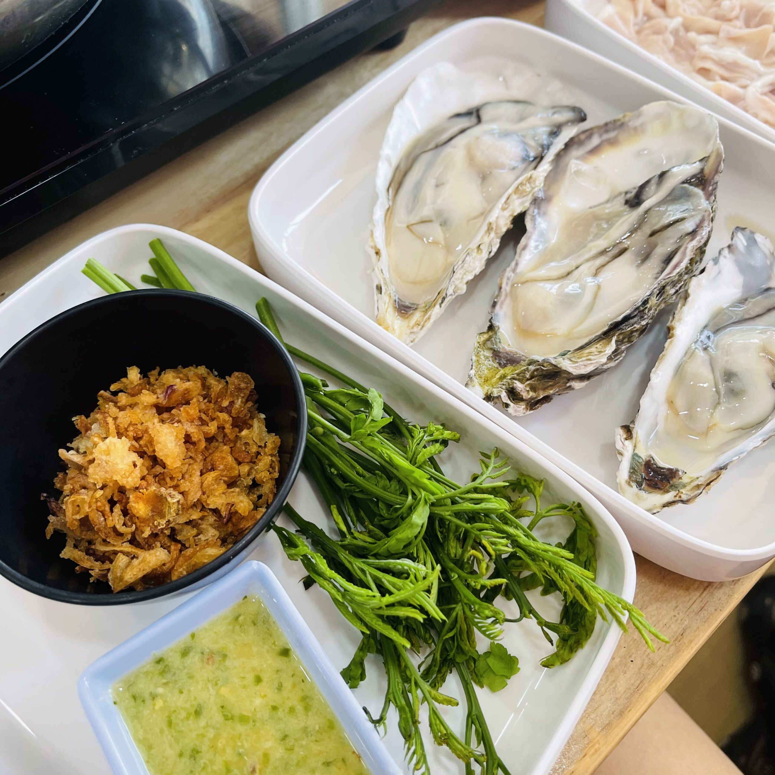 หอยนางรมสดบนเปลือกเสิร์ฟพร้อมผักสด กากหมู น้ำจิ้มซีฟู้ด และเนื้อหมูสไลซ์สำหรับชาบู