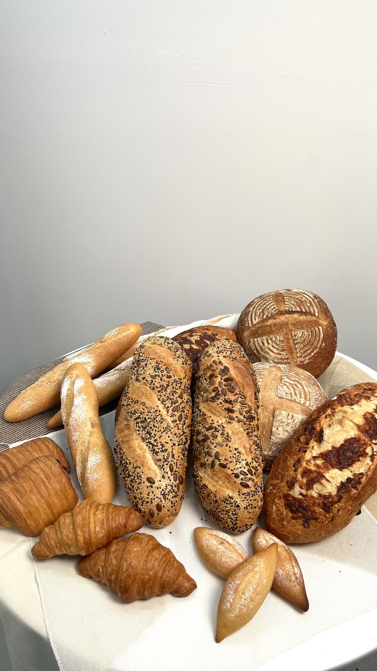 การจัดแสดงขนมปังหลากชนิดรวมถึงครัวซองต์ ขนมปังซาวร์โดว์ ขนมปังธัญพืช บาแก็ต และขนมปังชีสบนผ้าขาว