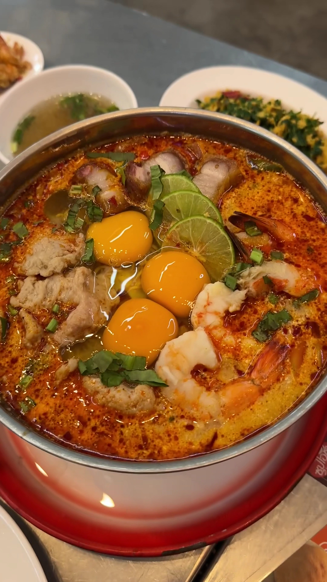 ต้มยำกุ้งน้ำข้นในหม้อแดง ใส่ไข่แดง 3 ฟอง กุ้งตัวใหญ่ มะนาว และผักชีซอย