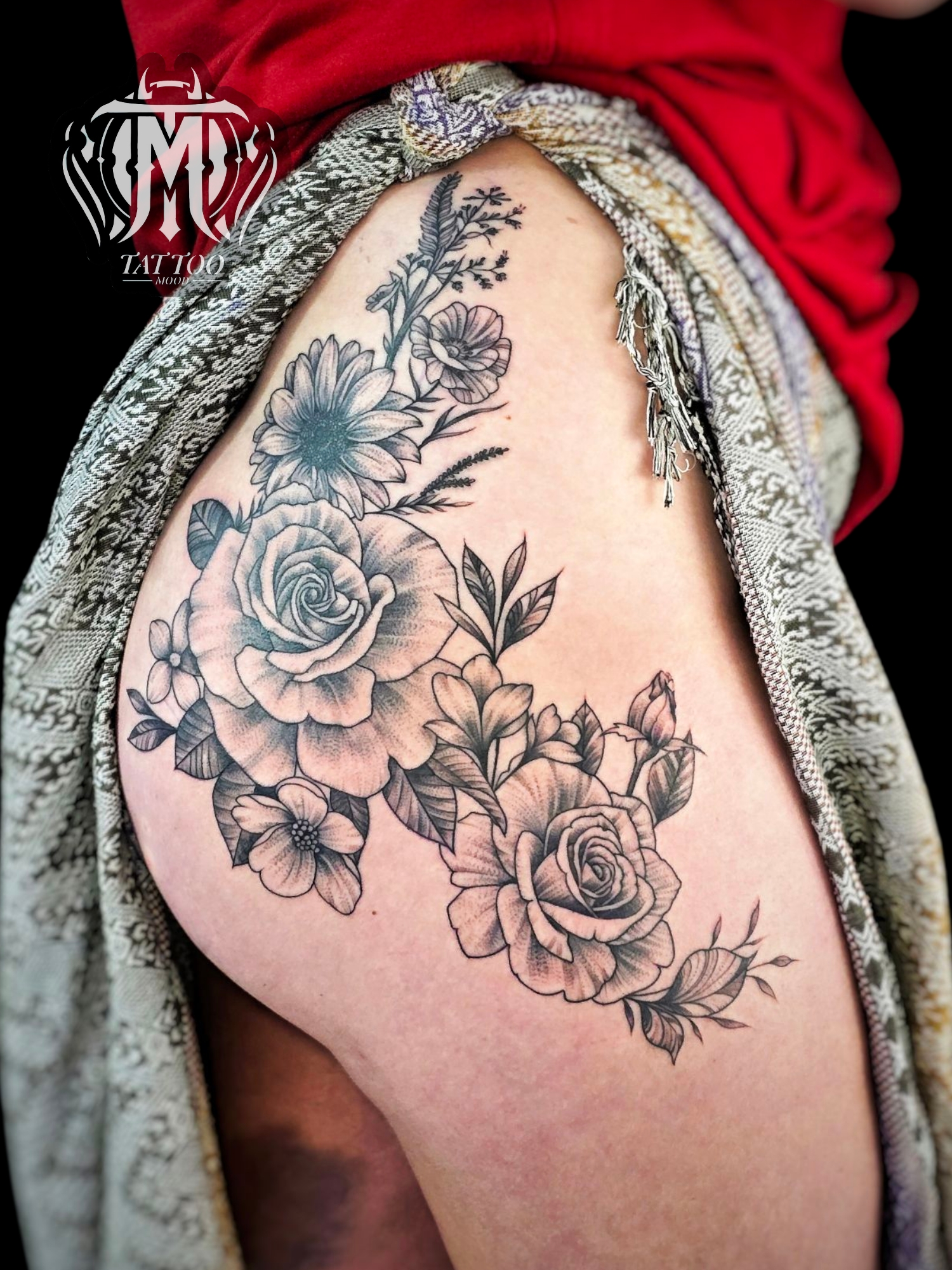 รอยสักลายดอกไม้ขาวดำบริเวณสะโพกและต้นขา มีดอกกุหลาบและดอกเดซี่