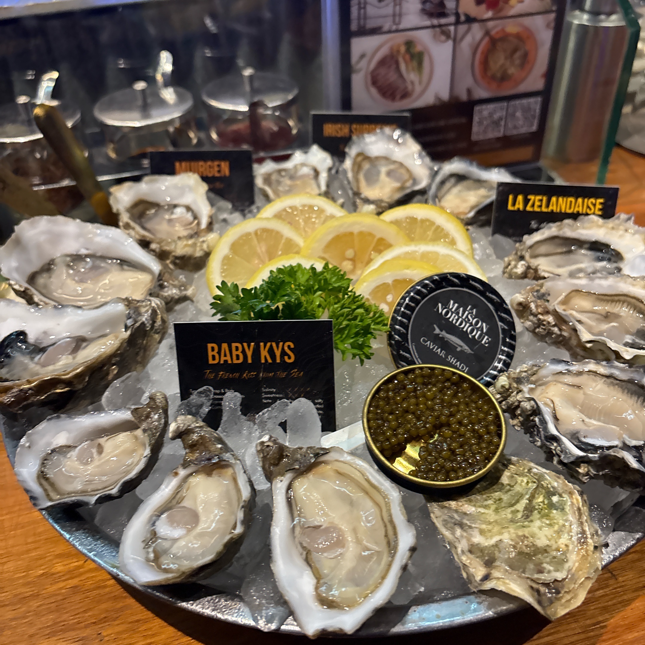 จานหอยนางรมสดหลากหลายชนิดบนน้ำแข็ง พร้อมคาเวียร์ La Maison Nordique มีหอย Murgen, Irish, Baby Kys และ La Zelandaise พร้อมเลมอนฝานและผักชีฝรั่ง