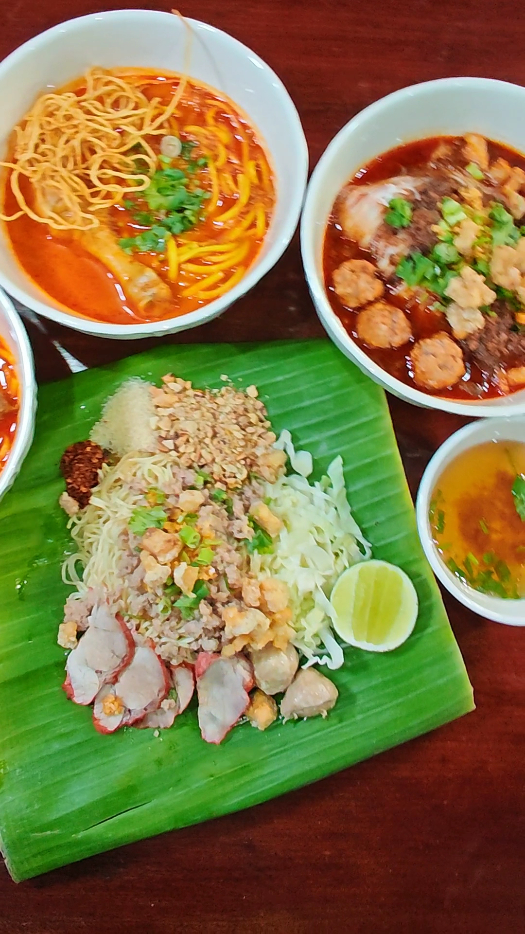 อาหารไทยหลายจาน ข้าวซอย ก๋วยเตี๋ยวน้ำตก และบะหมี่แห้งหมูแดงบนใบตอง พร้อมน้ำซุปเคียง