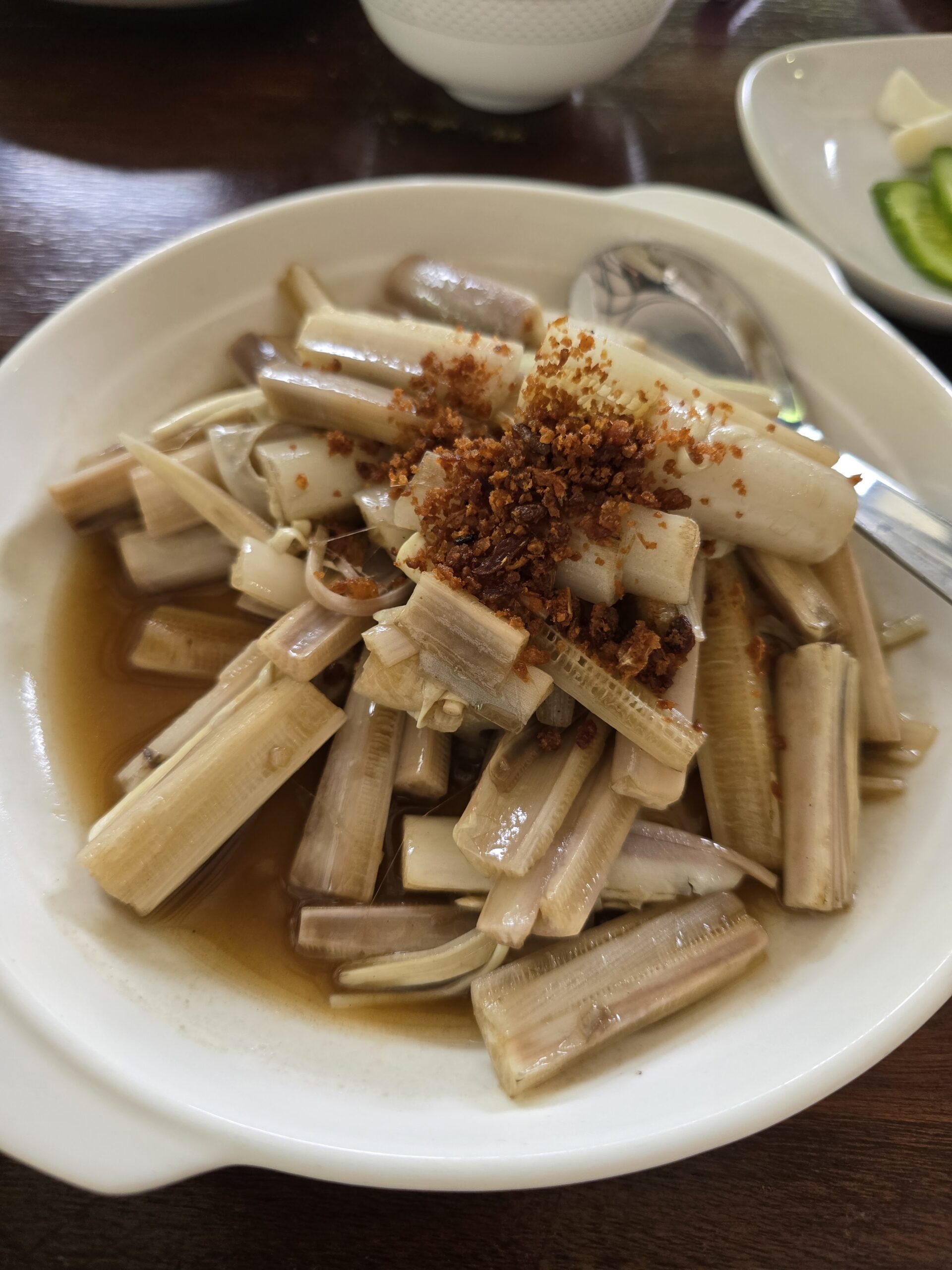 หอยมีดโกนนึ่งราดกระเทียมเจียวในจานสีขาว เสิร์ฟพร้อมน้ำซอส