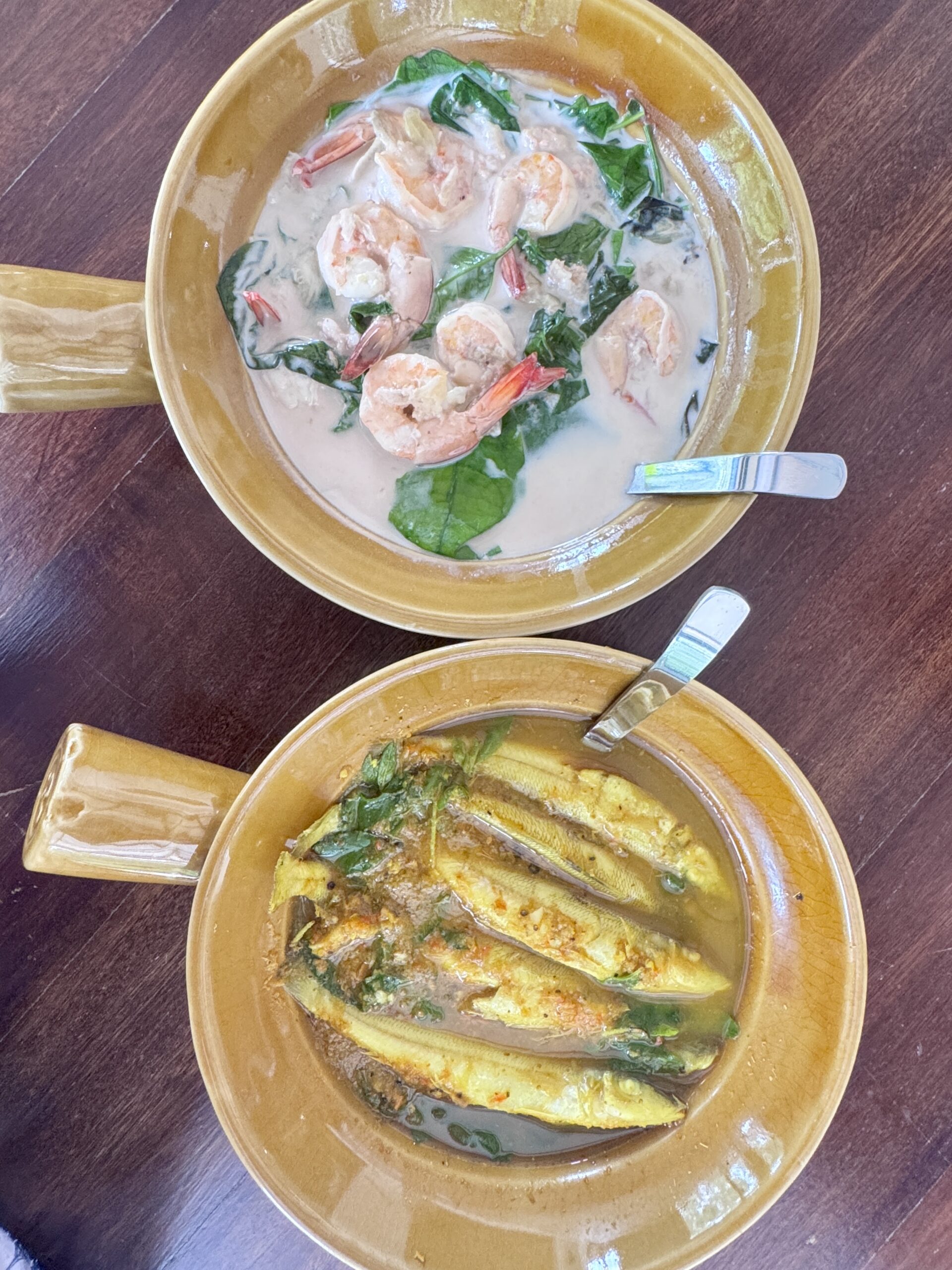 สองชามอาหารไทย แกงกะทิกุ้งใบโหระพาและปลาทอดราดน้ำแกงเหลืองในชามดินเผาสีน้ำตาล