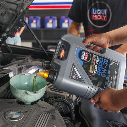 ช่างกำลังเทน้ำมันเครื่อง Liqui Moly Top Tec 4600 5W-30 ลงในเครื่องยนต์รถยนต์ BMW