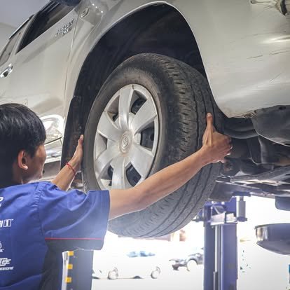 ช่างซ่อมรถกำลังเปลี่ยนยางรถยนต์ที่ยกขึ้นในอู่