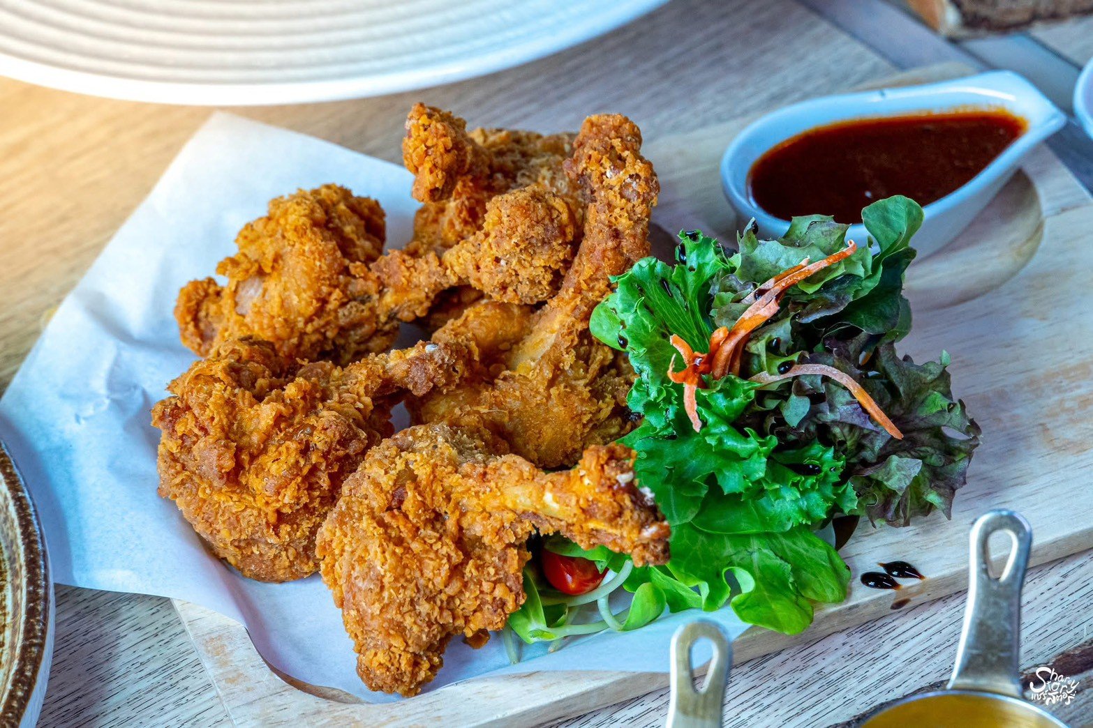 ไก่ทอดกรอบเสิร์ฟบนเขียงไม้พร้อมสลัดผักสดและน้ำจิ้มรสเข้มข้น