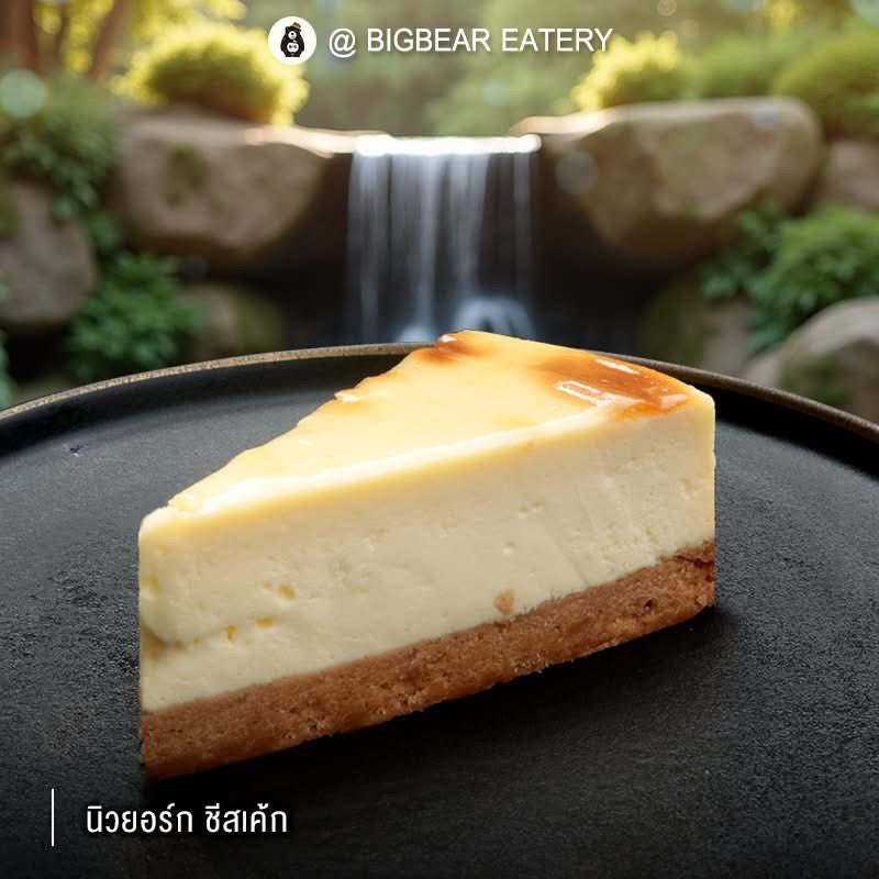 นิวยอร์กชีสเค้กชิ้นสวยบนจานดำที่ร้าน Bigbear Eatery พร้อมฉากหลังน้ำตกตกแต่งสวยงาม